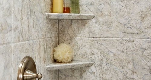 Closeup of the corner of a shower stall showing a built-in corner caddie hold bathing products.