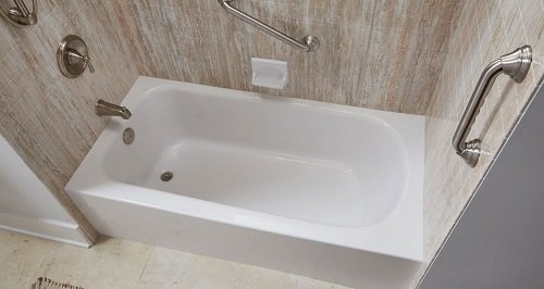 A standard bathtub with acrylic wall surrounds and grab bars.